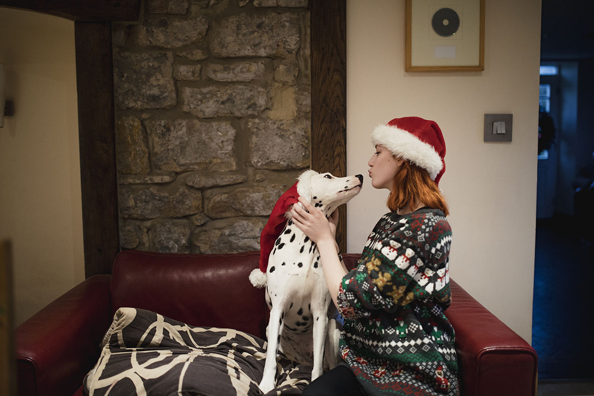 Young woman sitting on a couch with her dog during the holidays