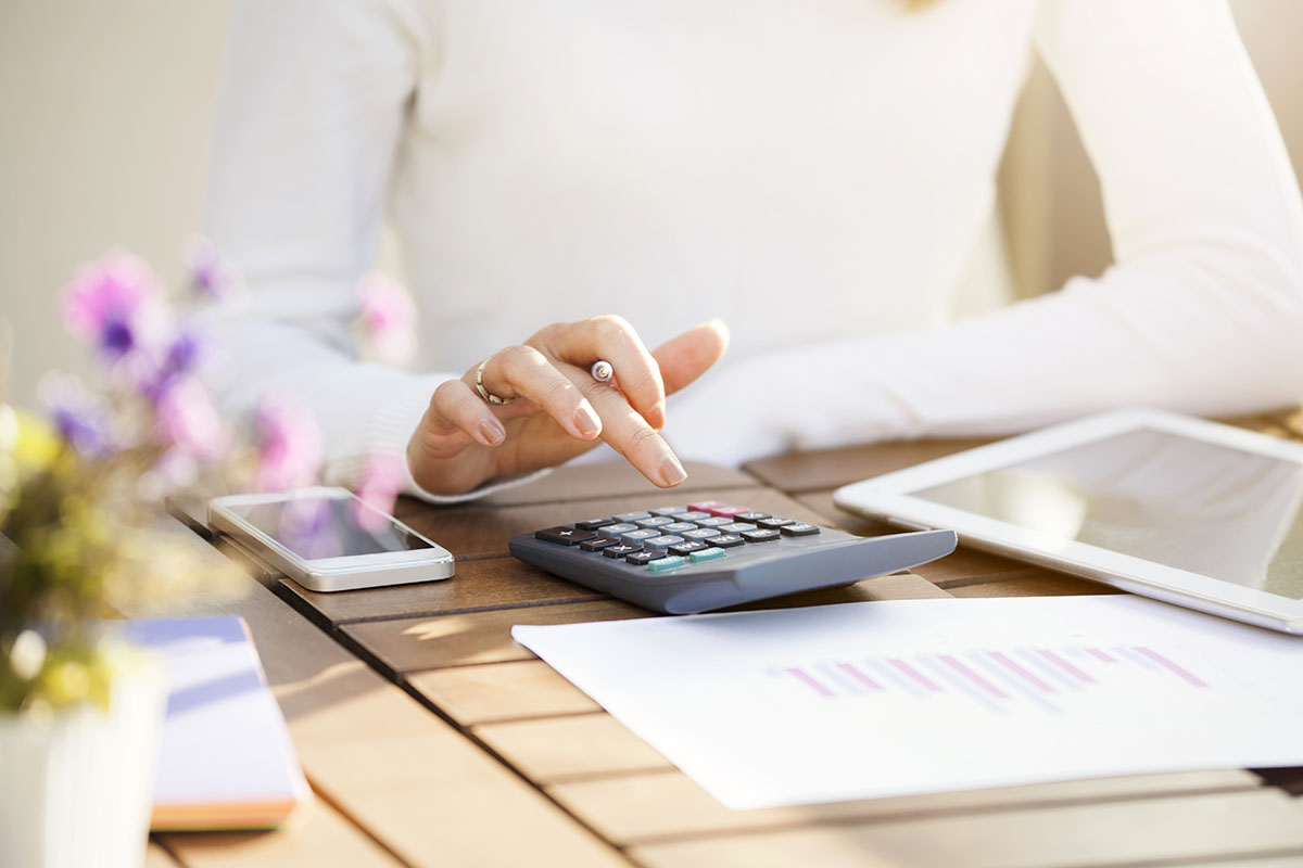 woman using calculator to budget finances at home