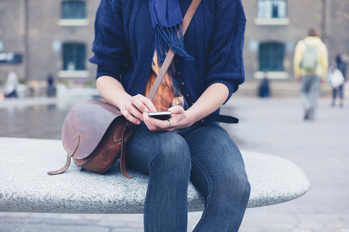 college student using smartphone outdoors on campus