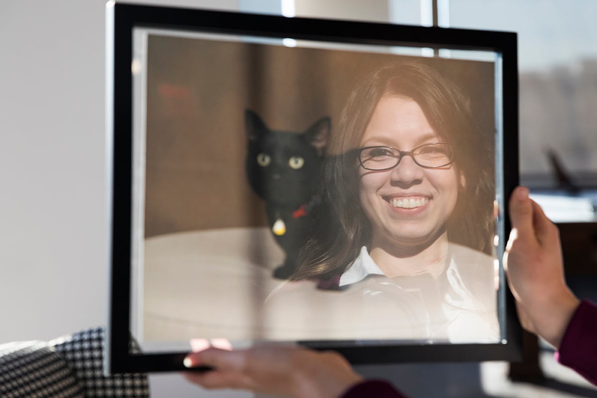 A woman reflection shows up in a portrait of her black cat.