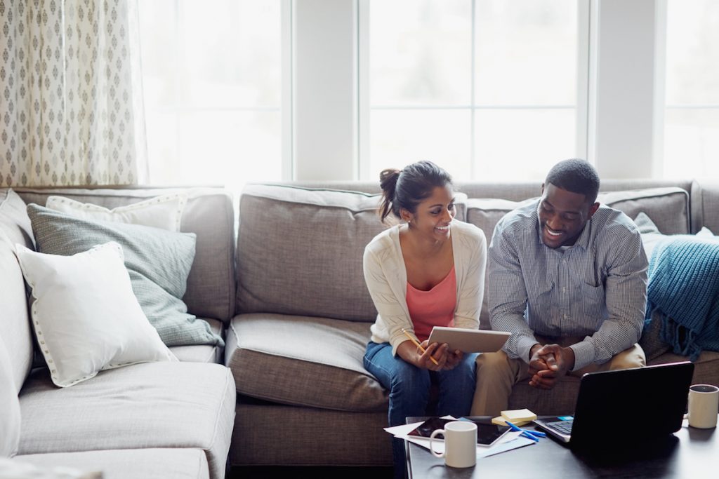 Shot of a young couple going through paperwork together on the sofa at home
