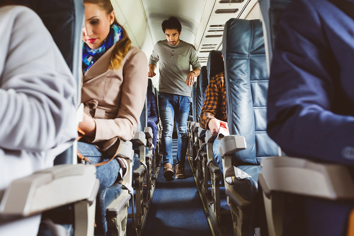 A man walks to his seat while on an airplane.