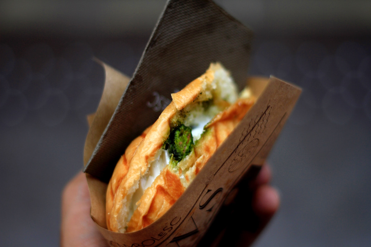 a hand holding out a sandwhich