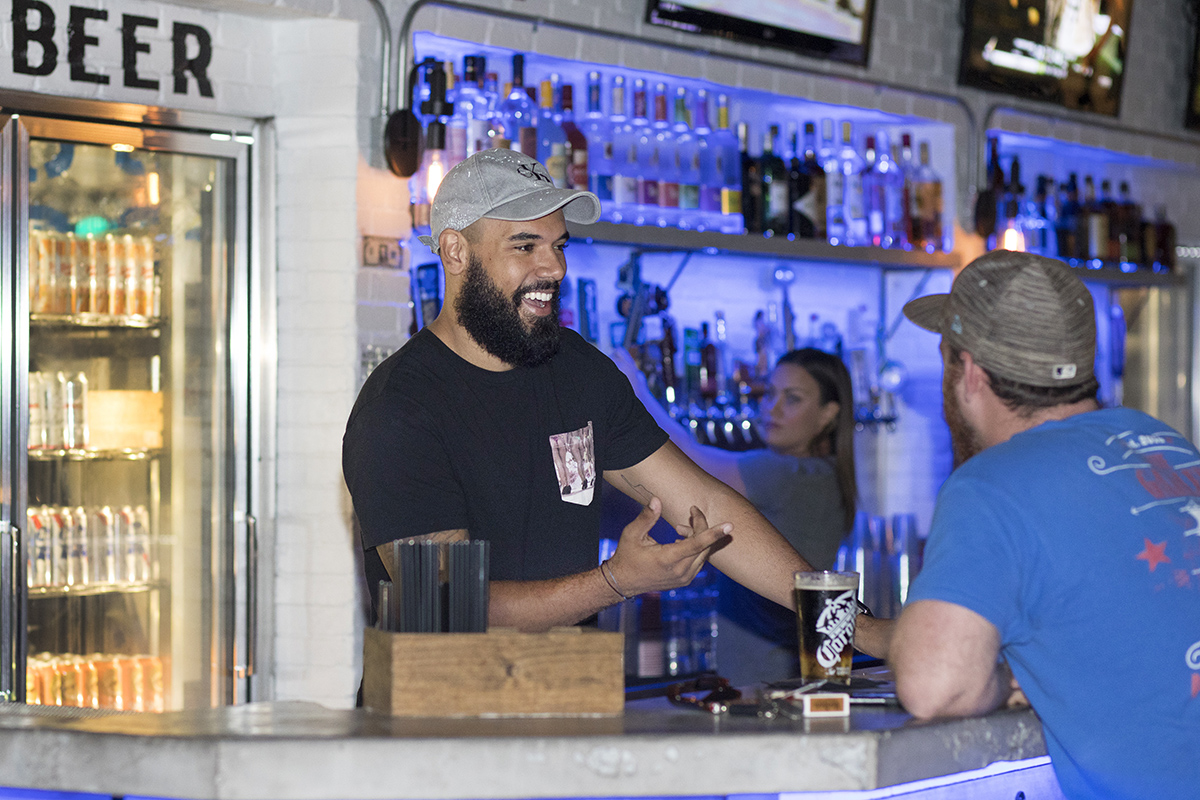 A bartender and bar patron interact at a bar in Florida.