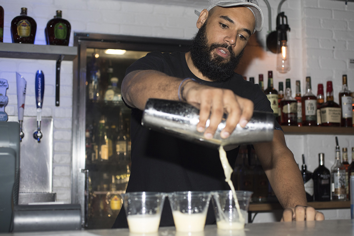 A young bartender makes drinks for customers at a bar in Florida.