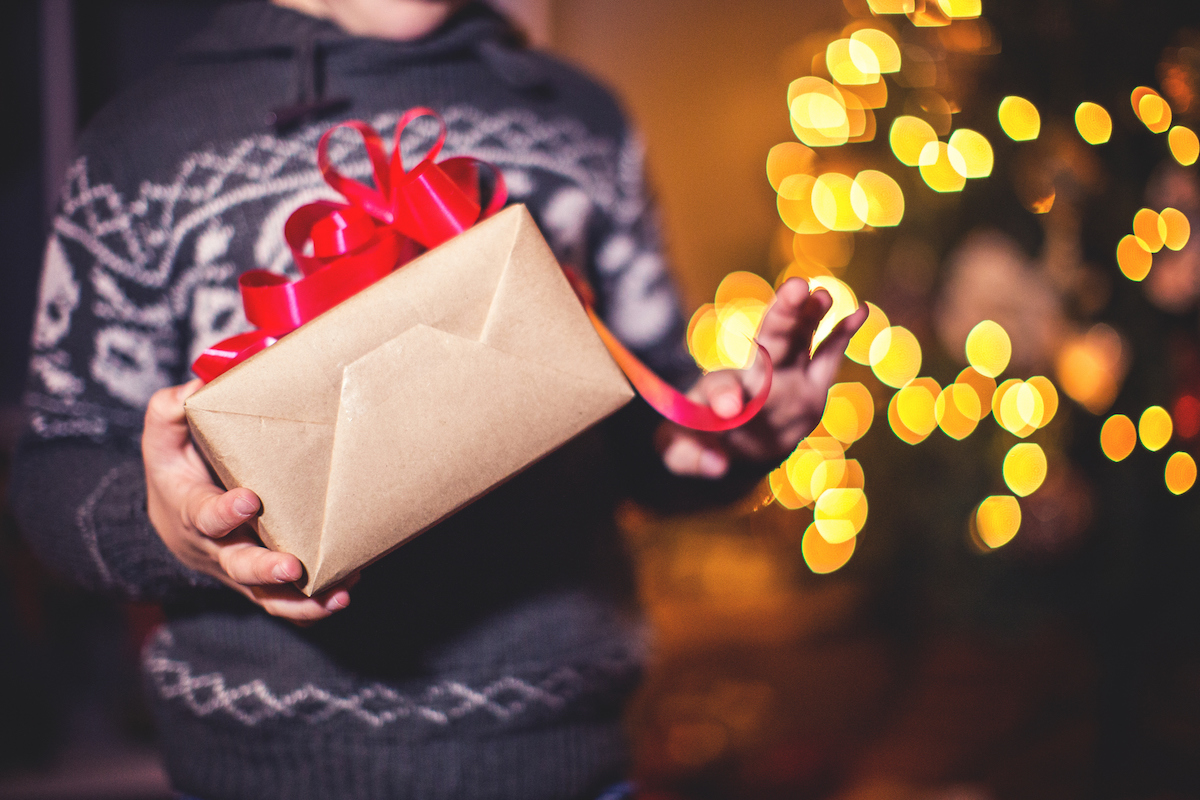 Closeup of child holding holiday gifts,by the Christmas tree