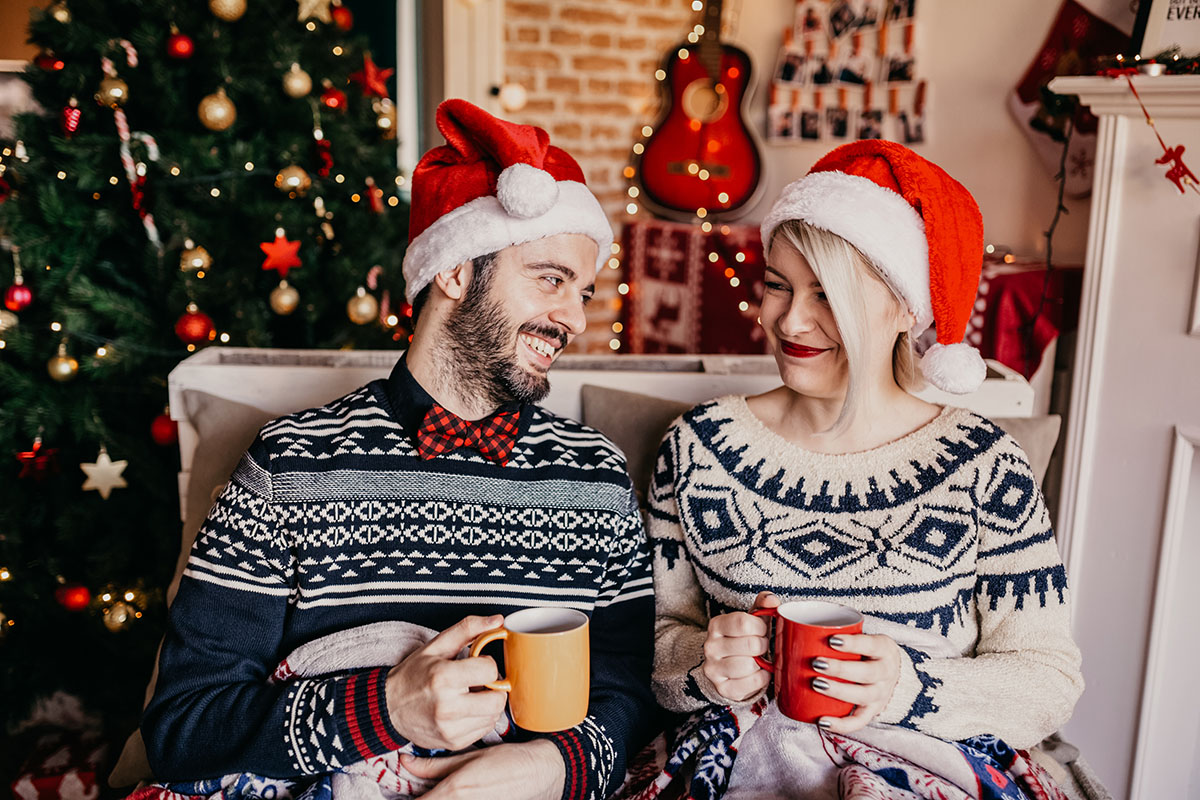 Couple relaxing and drinking tea in front of a Christmas tree