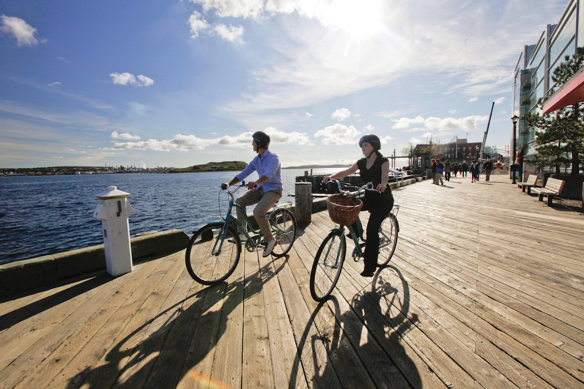two people riding bikes on a boardwalk