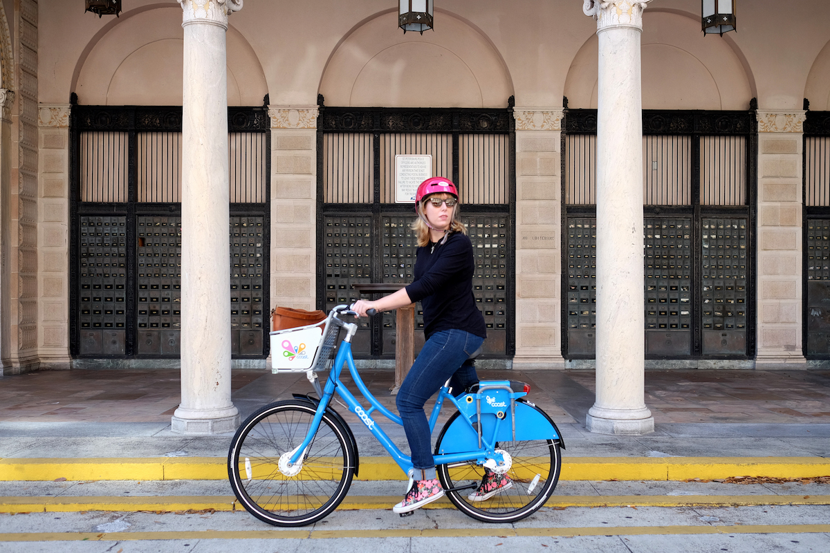 lisa rowan on a bike share bike outside of a post office