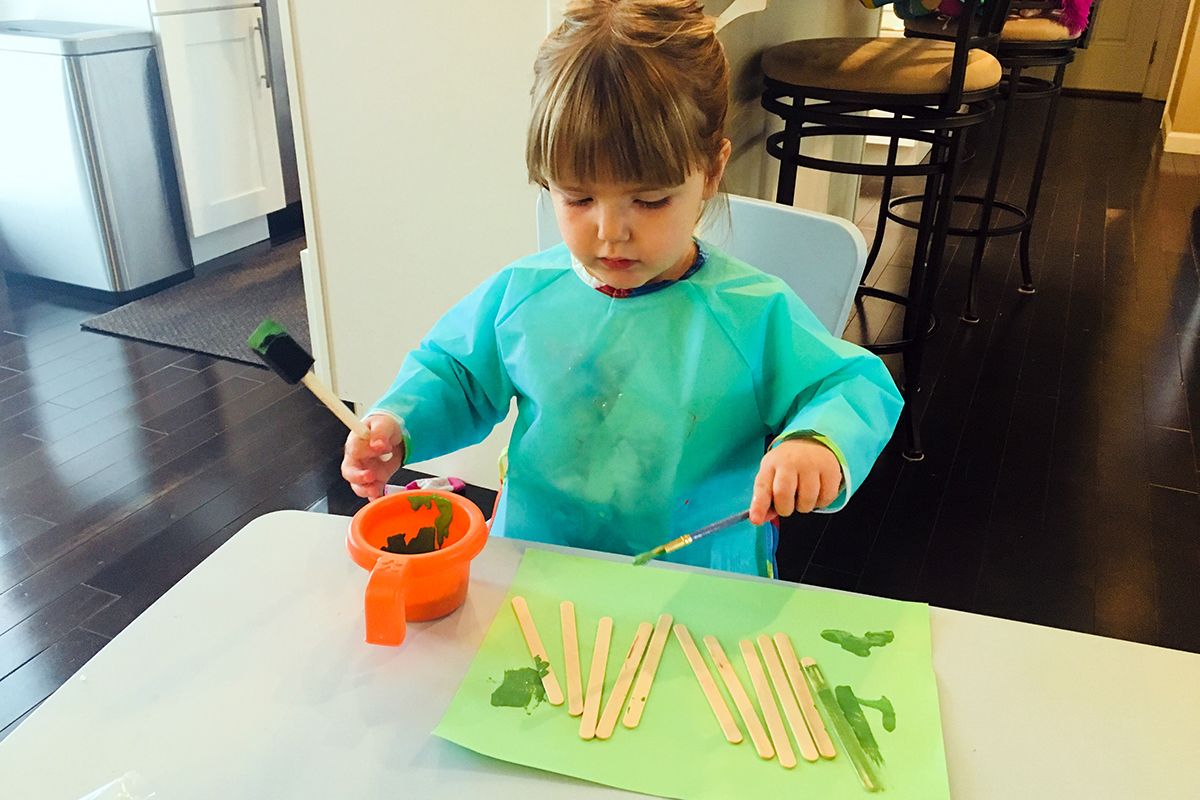 a little girl crafting with popsicle sticks