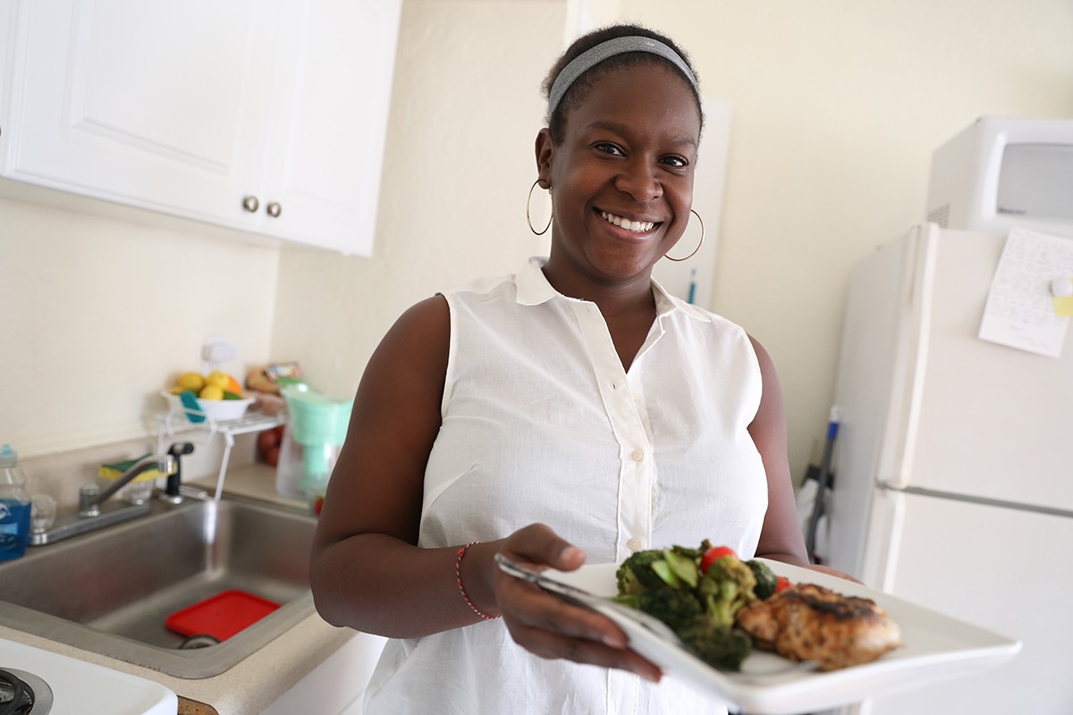 A young woman holds a freshly prepared lunch that's Whole 30 compliant.