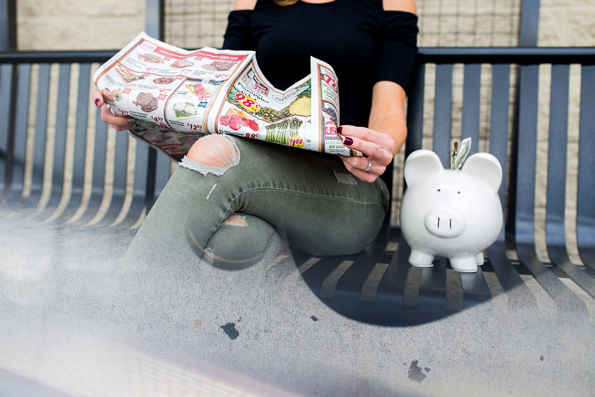 A woman looks at coupons outside of a grocery store.