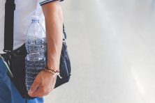 An adult man carrying a backpack and a bottle of water.