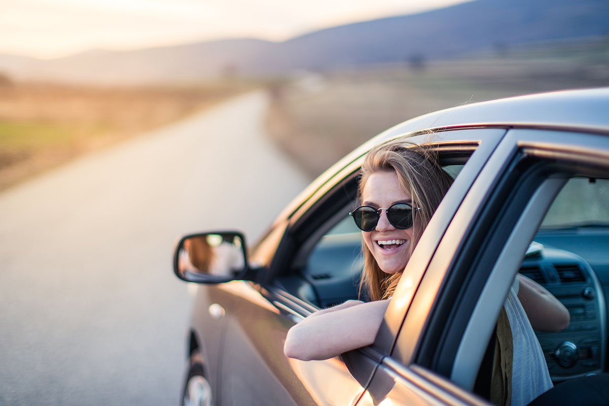 young woman sitting in the car on the country road