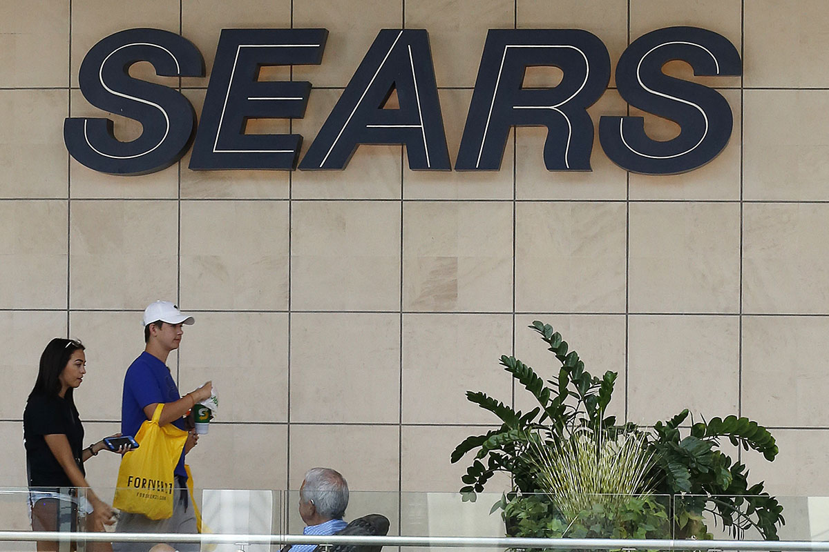 Shoppers walk by the sign at a Sears store in Pittsburgh