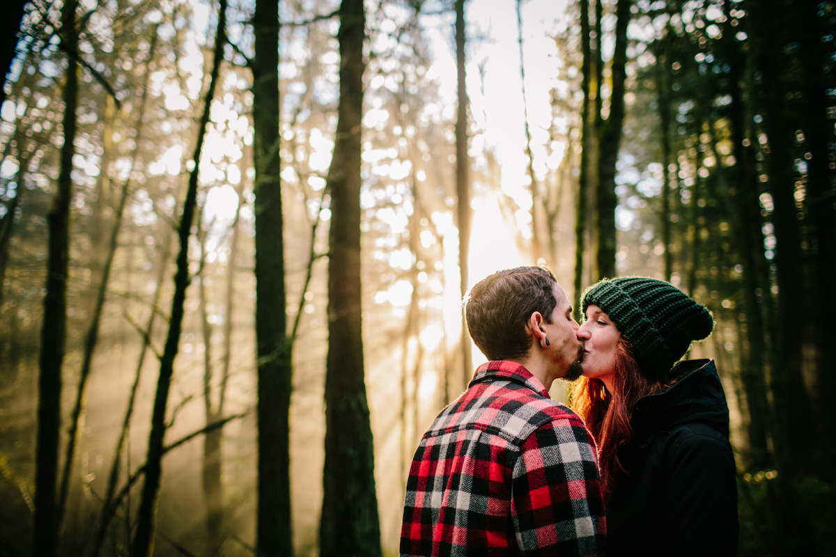a young couple kissing in a forest