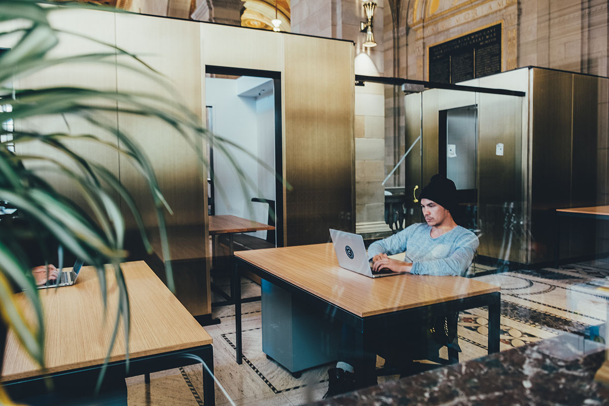 Omni Hotels Is Filling Work From Home Jobs In Atlanta Man Sitting At Desk In Cafe Or Lobby Working On His Laptop