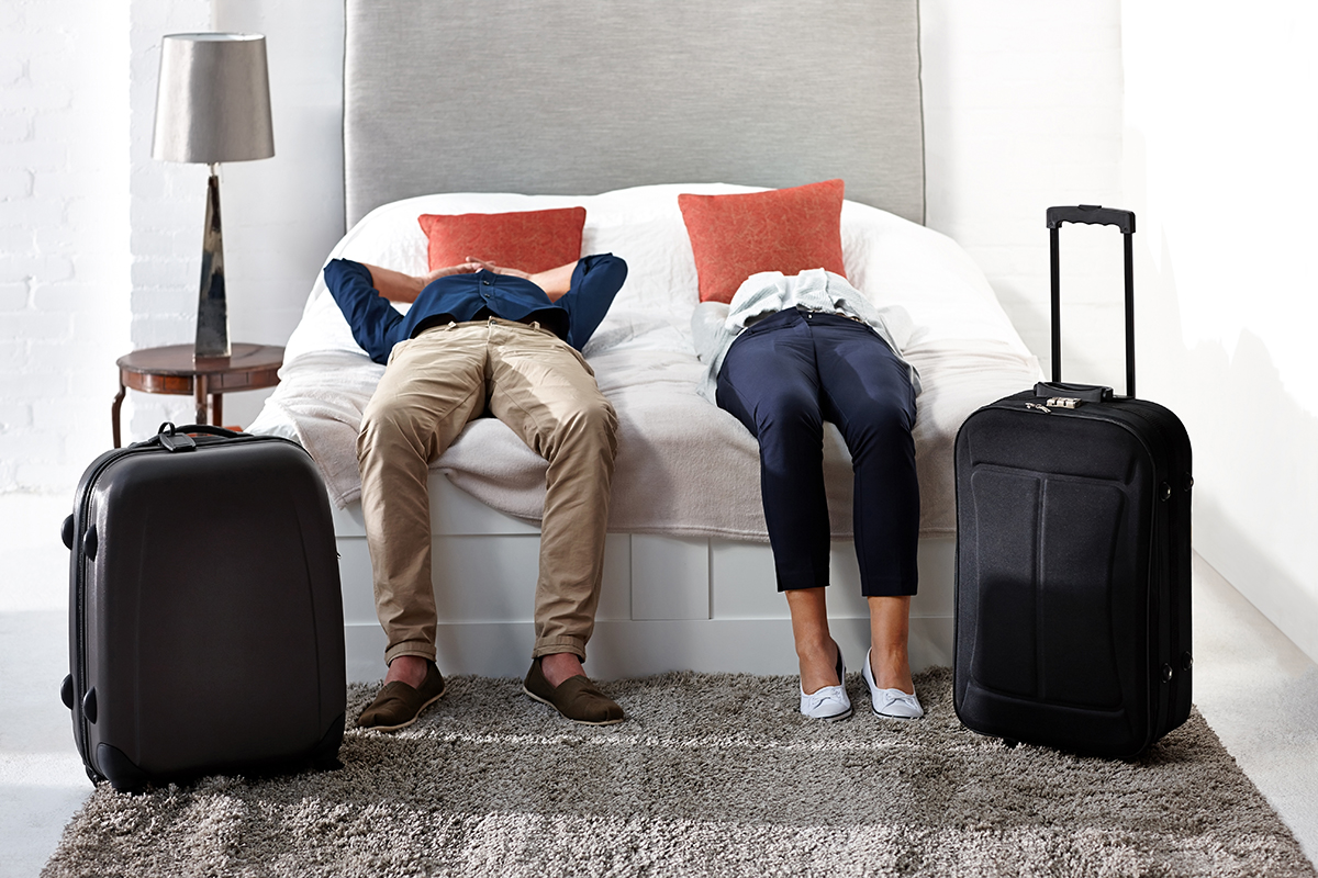 A couple lie on a hotel bed after checking into the hotel.