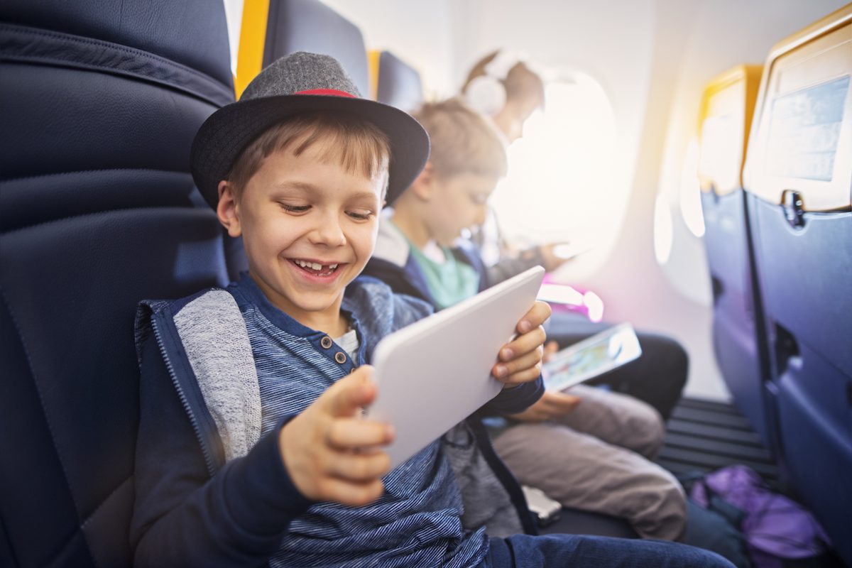 A child uses a tablet while traveling on an airplane.