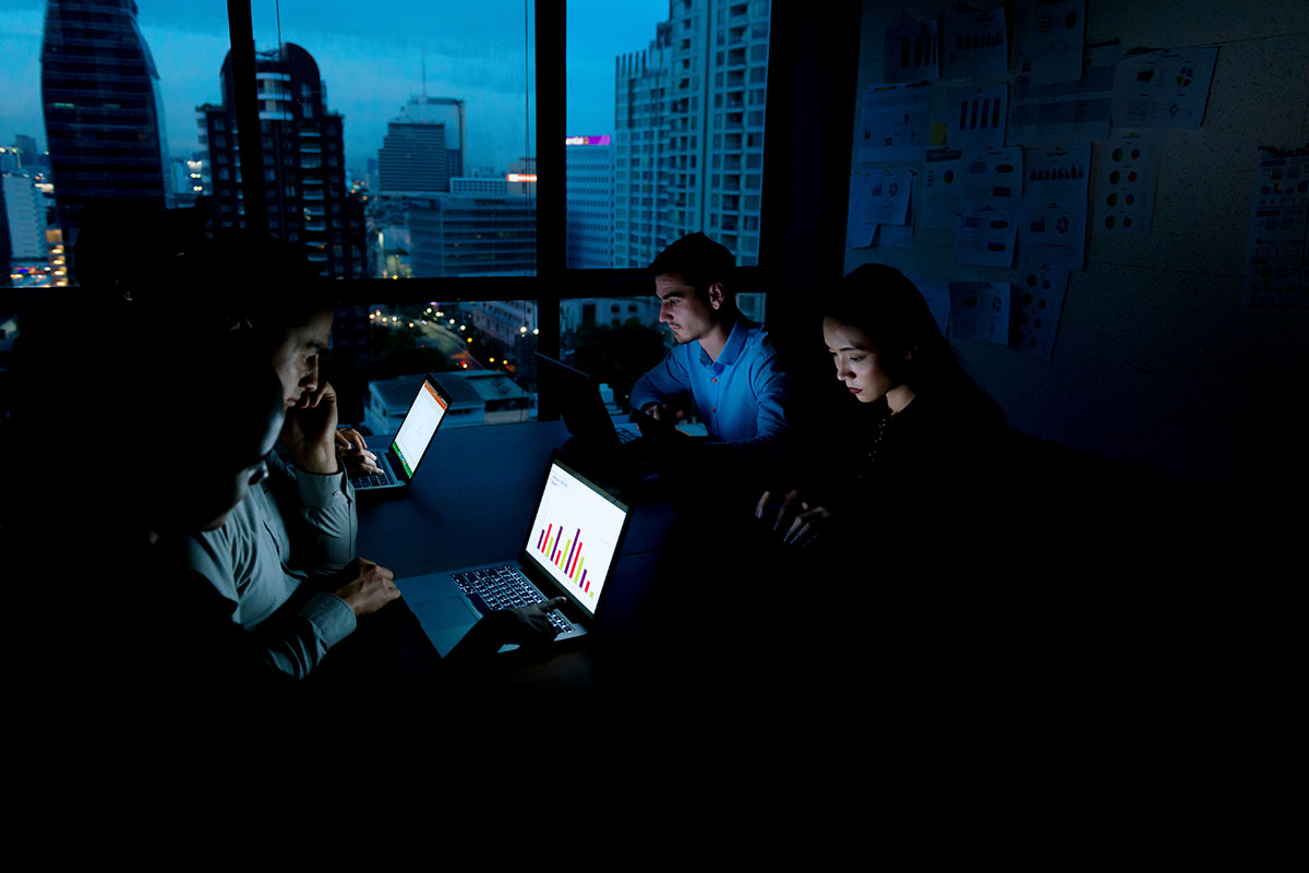 Group of young business team working late at night in meeting room trying to complete their assignments.