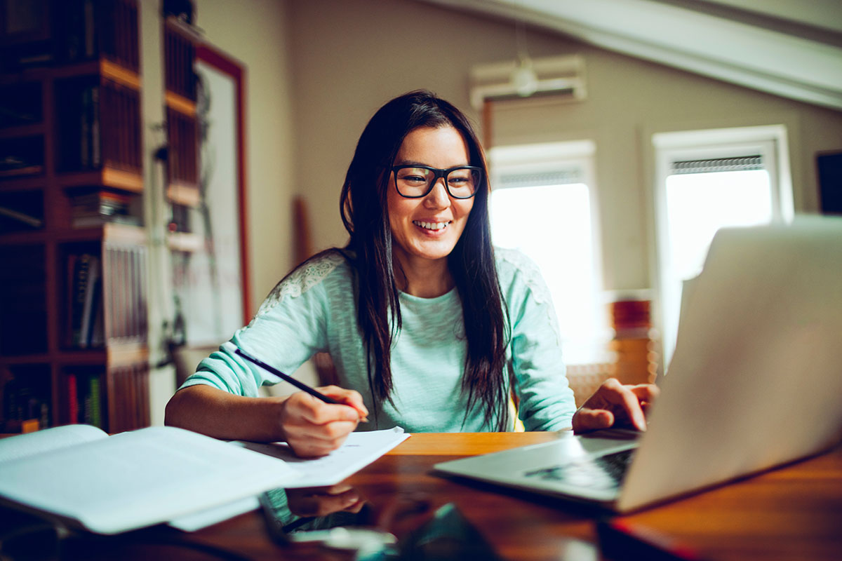 woman writing in front of computer in home office