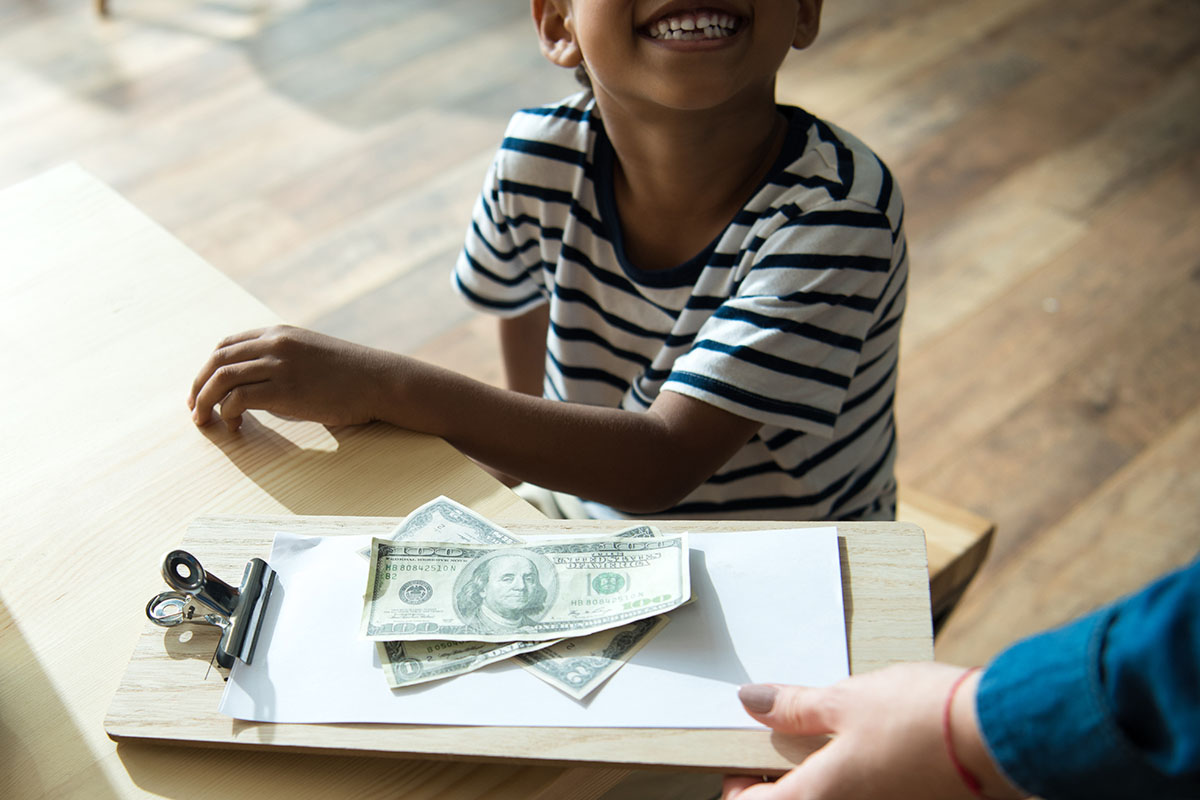 cropped shot of waiter holding bill and money while father with son sitting in cafe