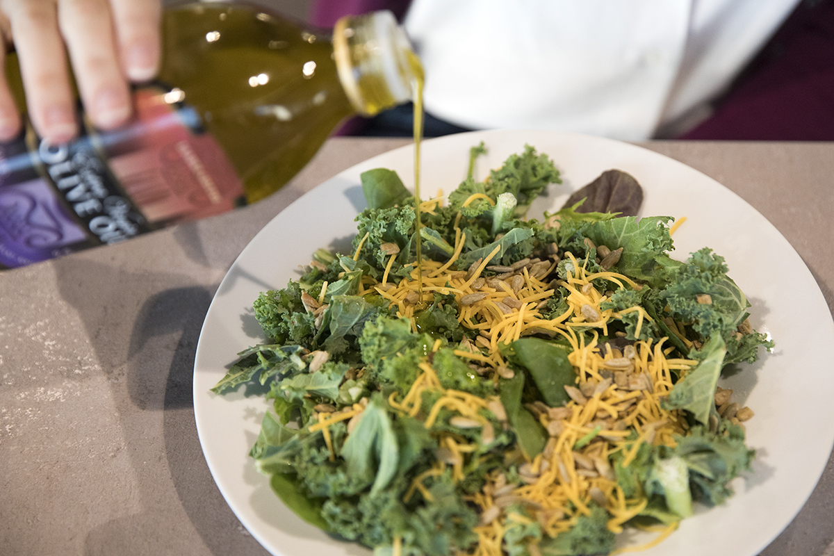A woman makes a spinach and kale salad.