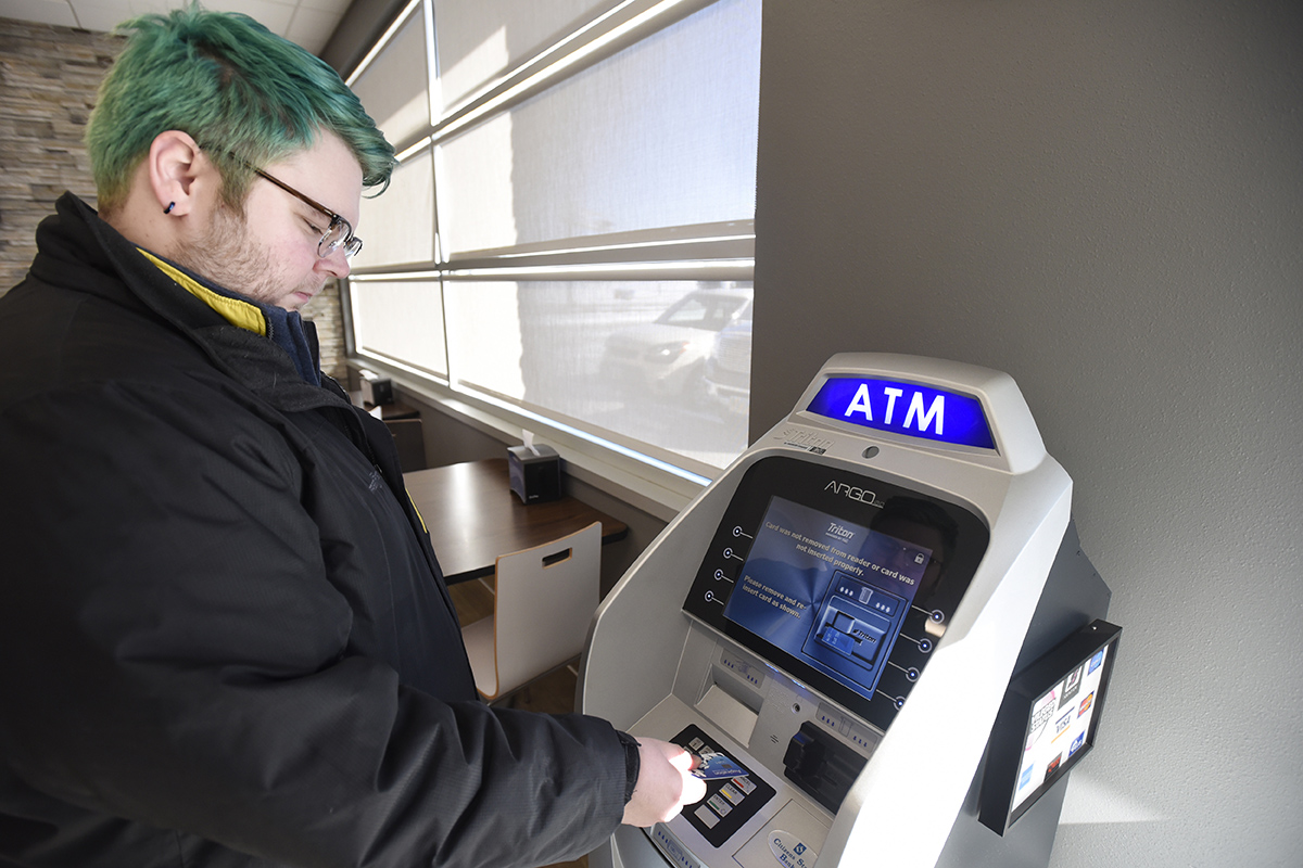 A man uses an ATM to get money out of his Aspiration bank account.