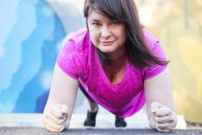 Marcie Hagner does a push up in front of a colorful mural as she talks about losing weight using Healthy Wage