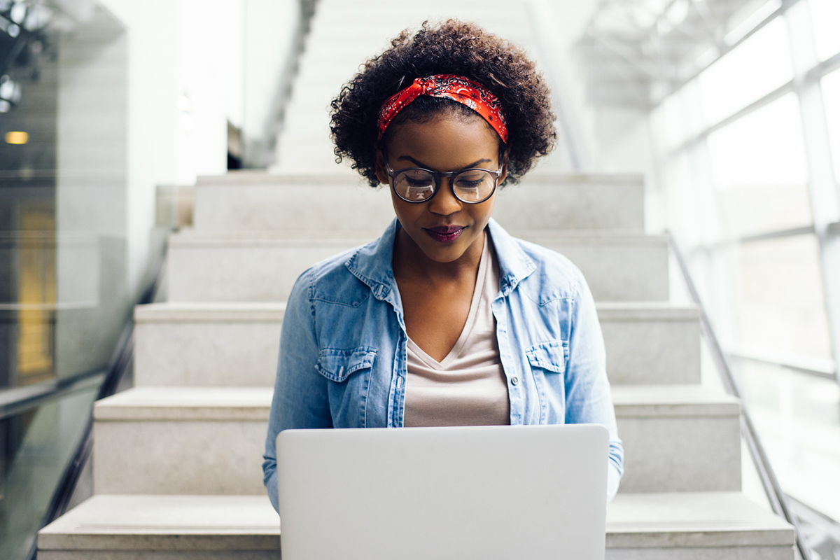 student with laptop sitting on staircase
