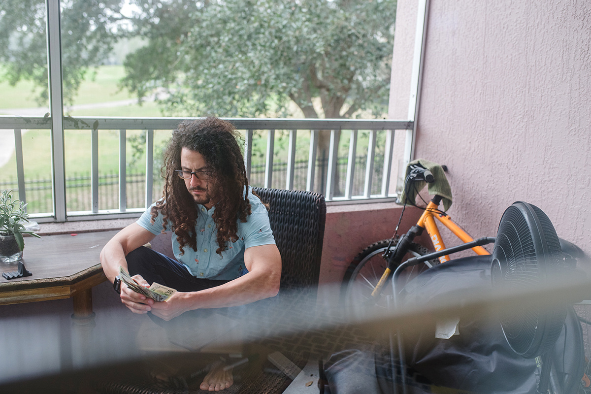 a young man sorts cash on his balcony.