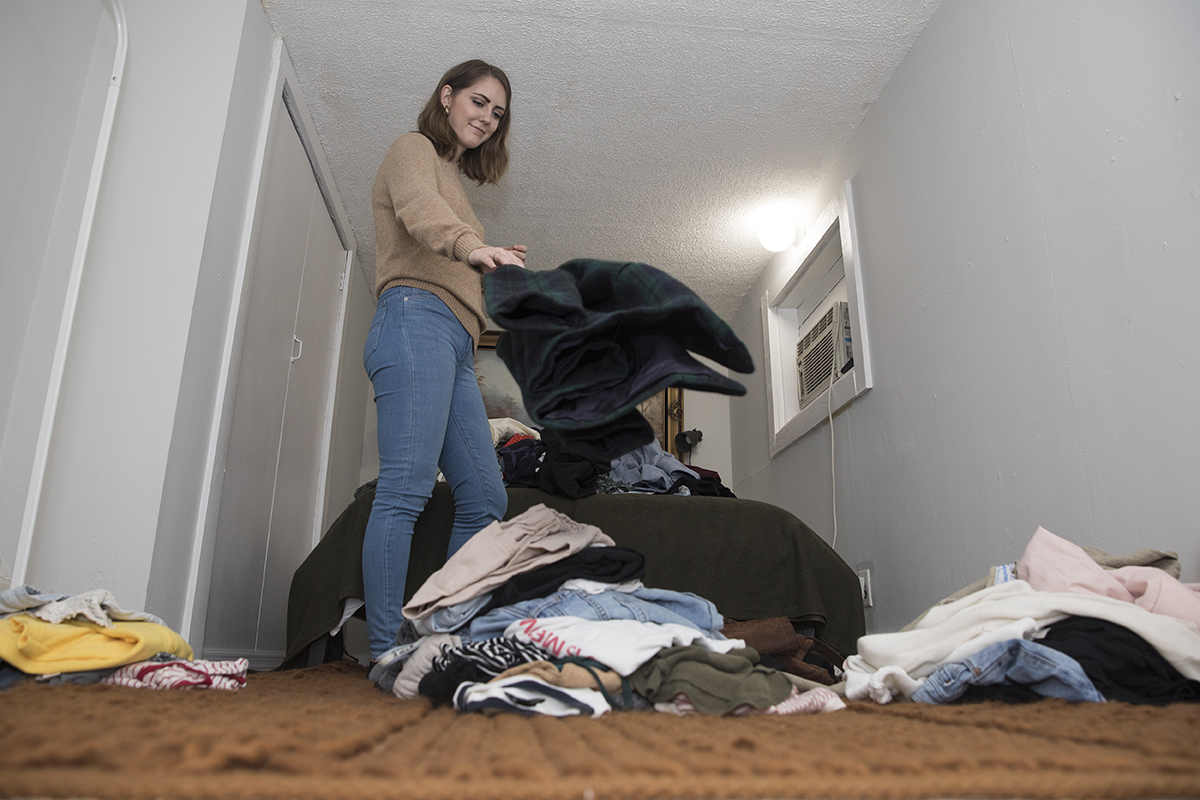 A woman creates piles of clothes she intends to keep, donate or still has to think about keeping or getting rid of.