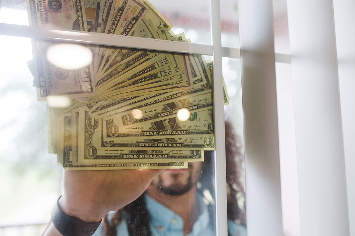 man holding up cash to window