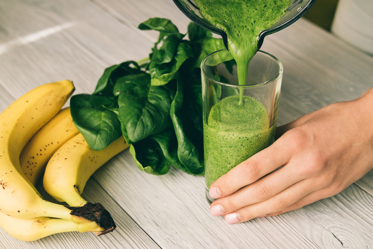 hand pouring smoothie into a glass