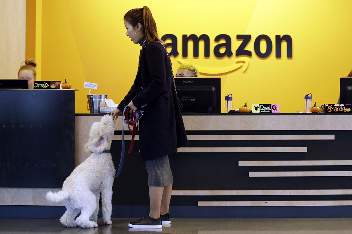 An Amazon employee gives her dog a biscuit as the pair head into a company building, where dogs are welcome, in Seattle