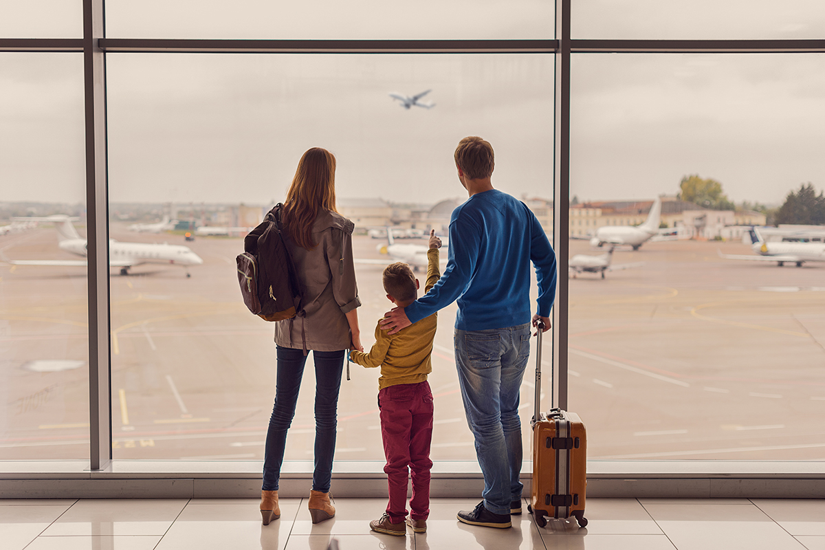 A family watches as airplanes take off for light and land at an airport.