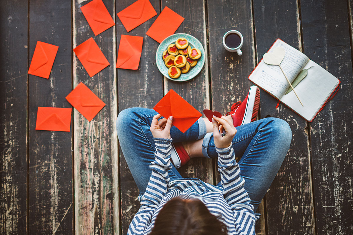 Young woman writing a valentine card - top view