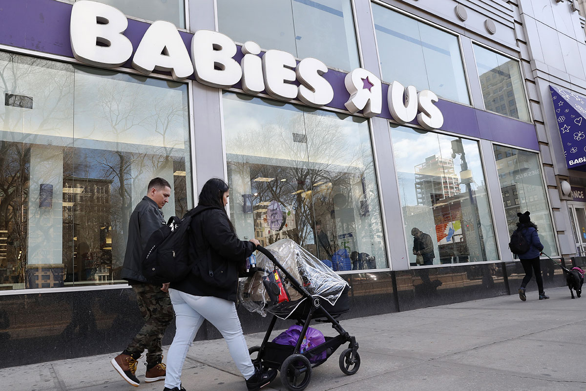 Queens residents Carlos Lopes, left, and Katiria Maldonado and their young child leave Babies R Us after shopping at Manhattan's Union Square store in New York,