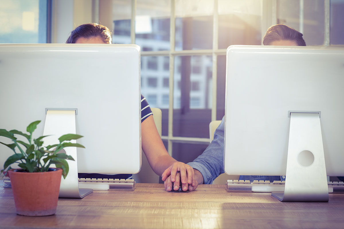 Couple holding hands at work in creative office