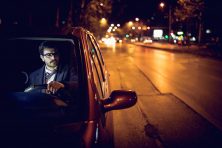 Businessman driving a car back home late at night, after a long day on the job.