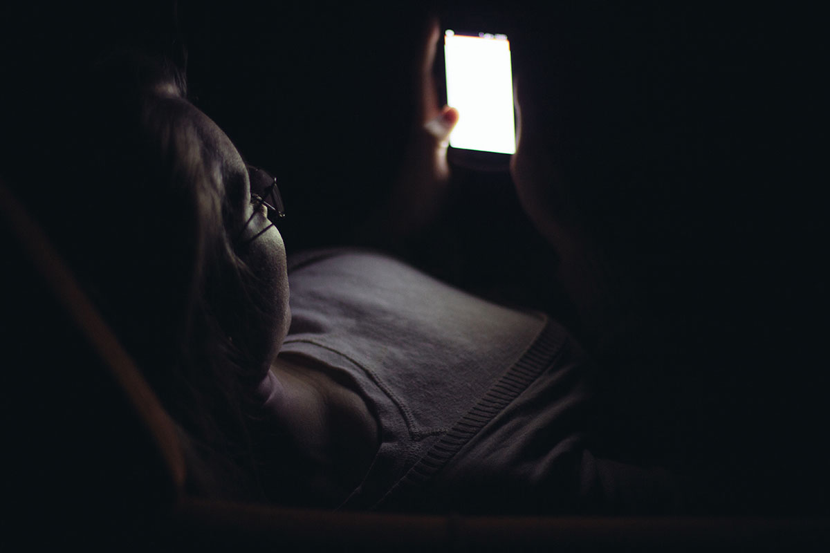 Young woman using mobile phone in dark room at night