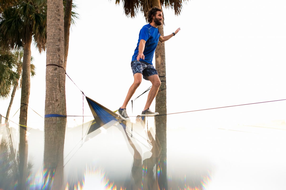 Man on tight rope with palm trees in Florida.