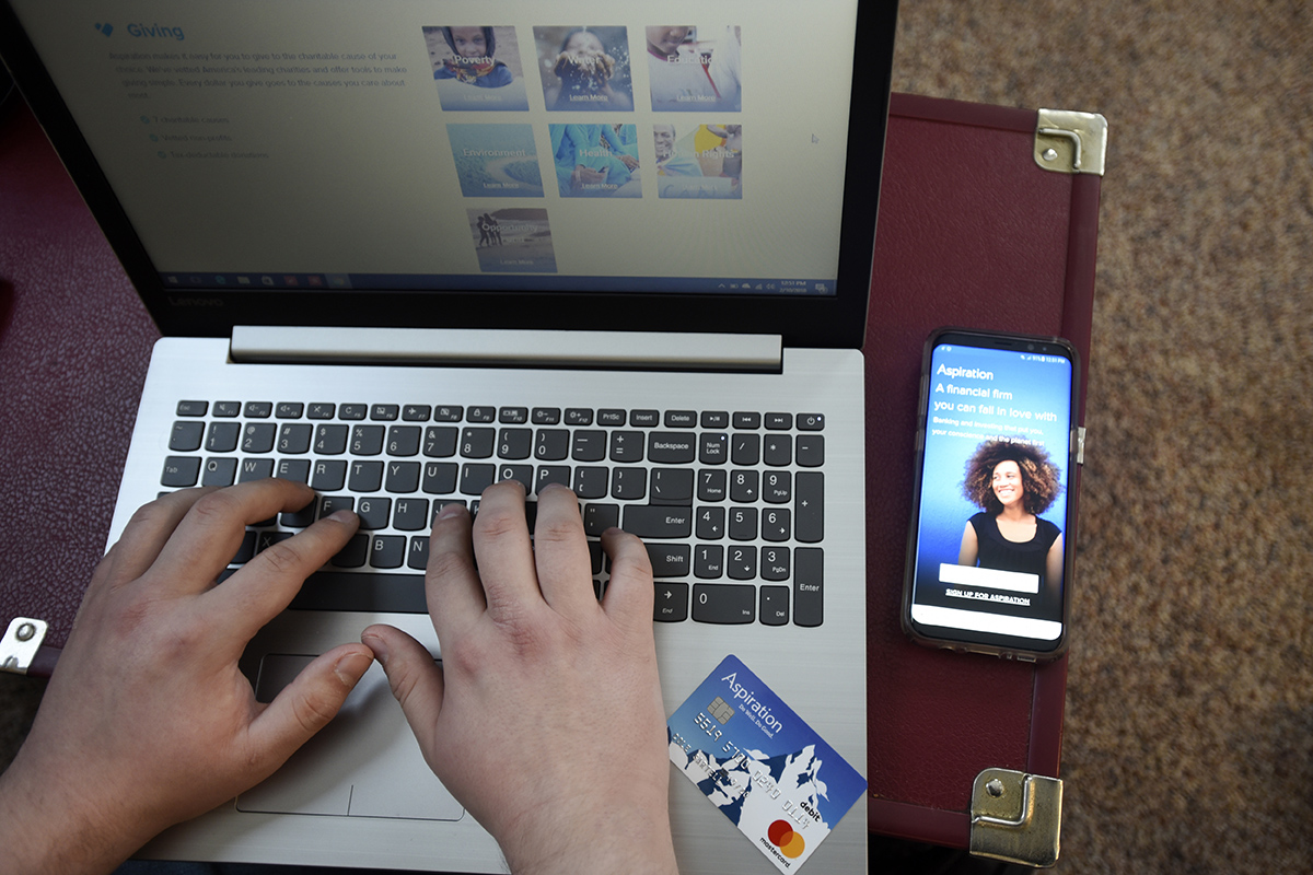 A man logs into his Aspiration account on his computer at home.