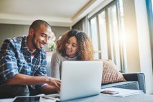A young couple check their credit on their laptop at home.