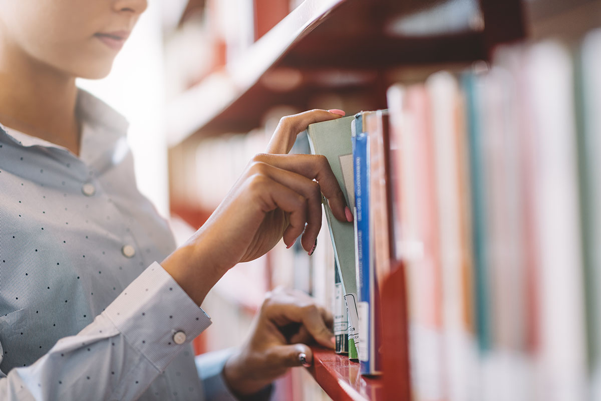 woman searching books on the bookshelf and taking a textbook on the shelf