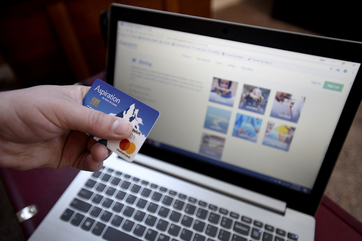 holding debit card up in front of laptop computer