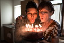 two women blowing out candles on birthday cake