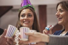 A woman in a party hat toasts with friends.