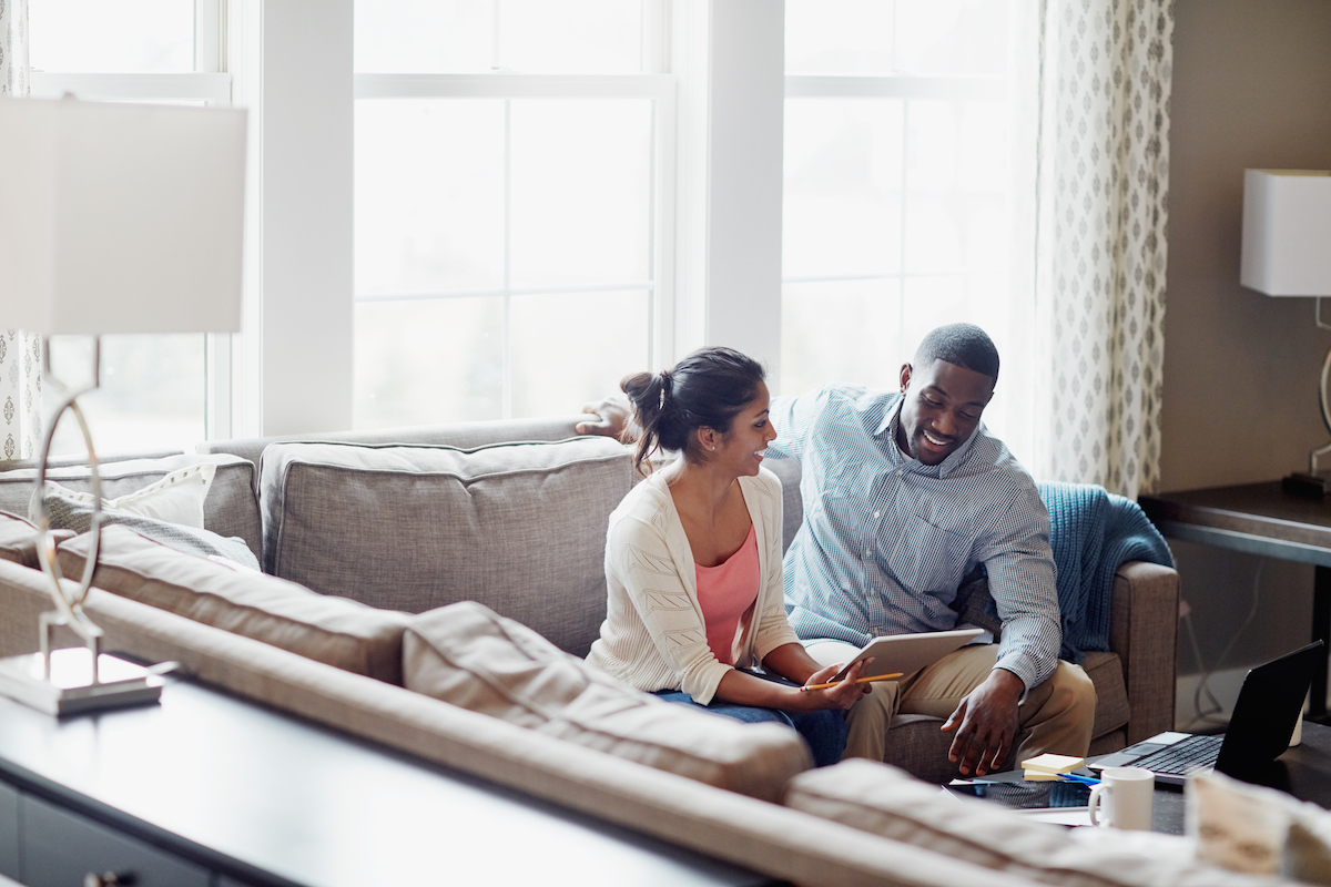 Shot of a young couple going through paperwork together on the sofa at home