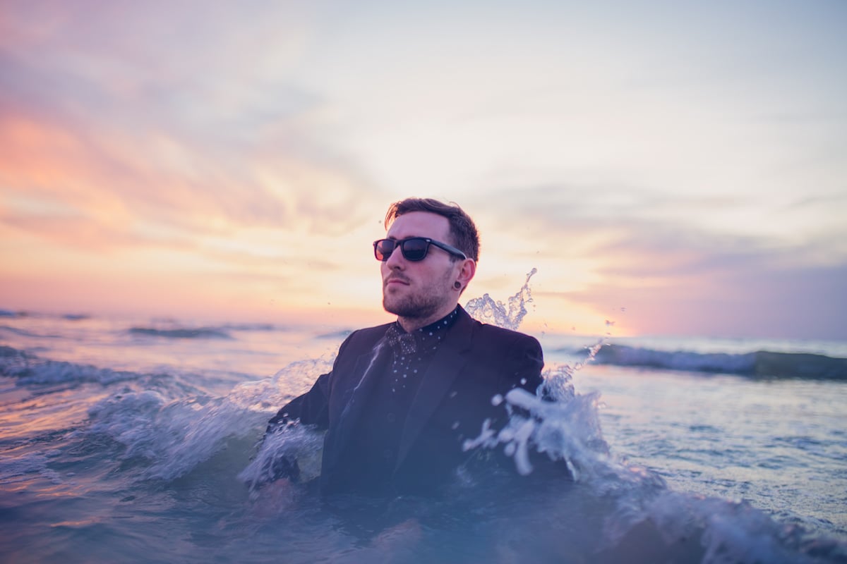 A man is hit by a small wave while wearing a suit